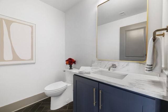 bathroom with baseboards, visible vents, vanity, and toilet