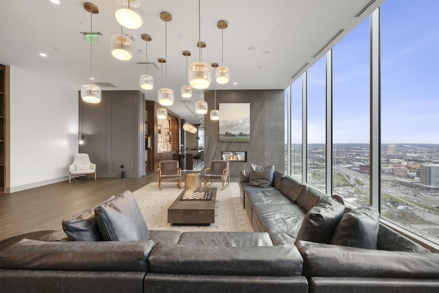 living area with floor to ceiling windows, a city view, baseboards, and wood finished floors