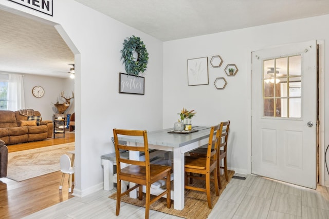 dining space featuring arched walkways, a ceiling fan, and baseboards