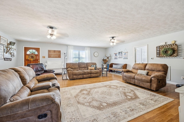 living area with a textured ceiling, a ceiling fan, and wood finished floors