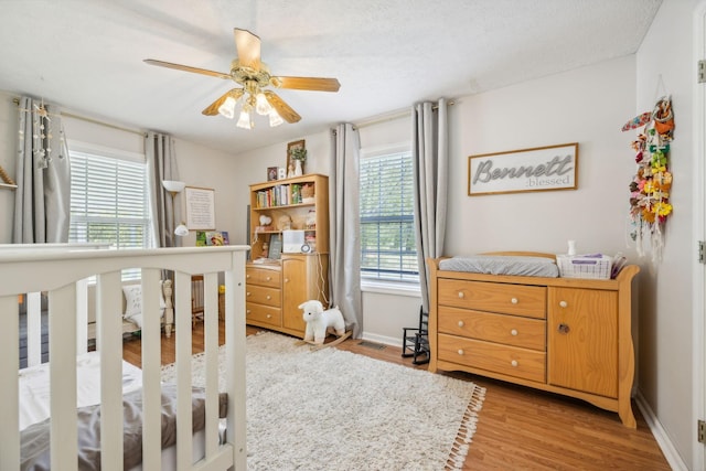 bedroom with light wood-style flooring, baseboards, and ceiling fan