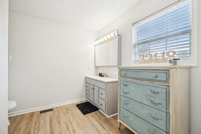 bathroom with baseboards, visible vents, toilet, wood finished floors, and vanity