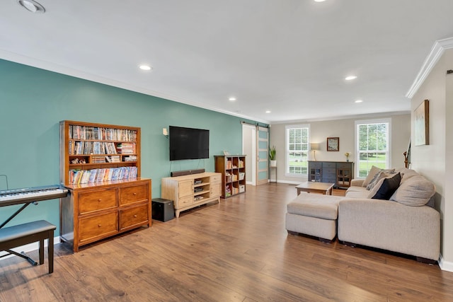 living room with a barn door, wood finished floors, and crown molding