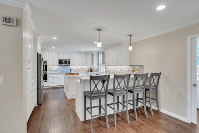 kitchen with visible vents, white cabinets, ornamental molding, a peninsula, and stainless steel appliances