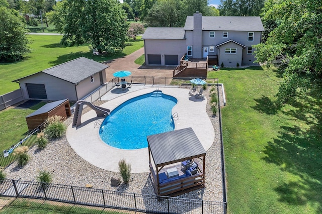 view of swimming pool featuring a patio, an outdoor structure, fence, a lawn, and a fenced in pool