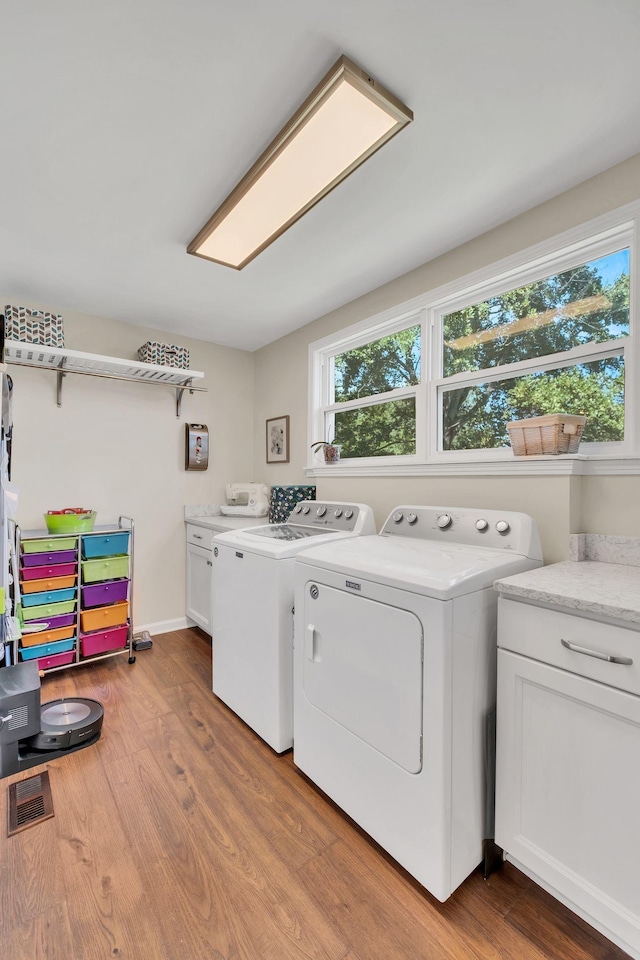 laundry room featuring cabinet space, visible vents, washer and dryer, and wood finished floors