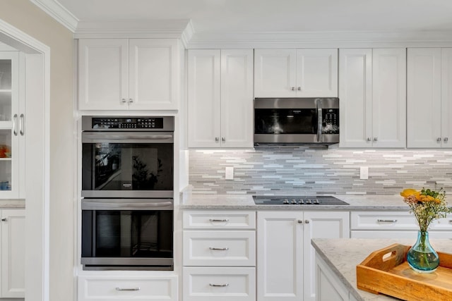 kitchen featuring stainless steel appliances, white cabinetry, light stone counters, and decorative backsplash