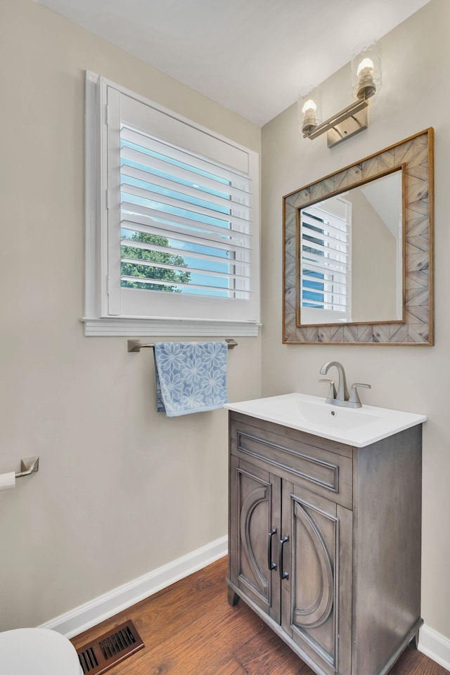 bathroom with toilet, wood finished floors, vanity, visible vents, and baseboards