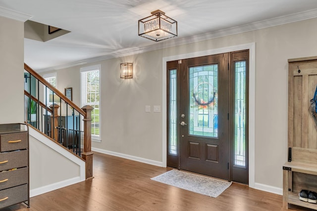 entrance foyer with stairs, baseboards, wood finished floors, and crown molding