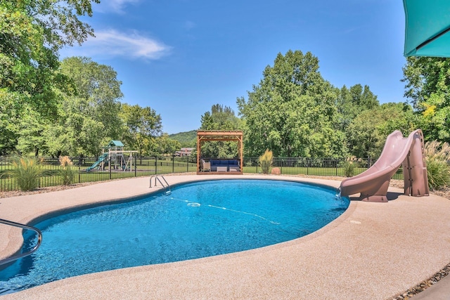 view of swimming pool featuring a water slide, a playground, fence, and a jacuzzi