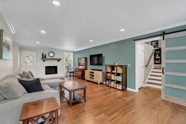 living room featuring a barn door, crown molding, wood finished floors, and recessed lighting