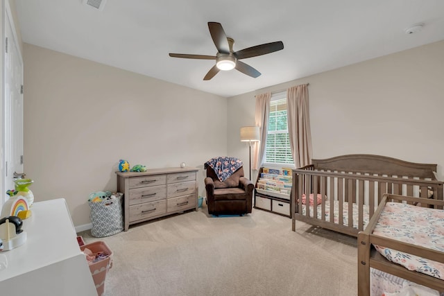 bedroom with a crib, carpet, and ceiling fan