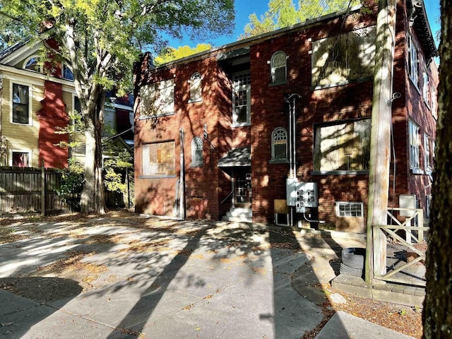 view of front of house featuring entry steps, brick siding, and fence