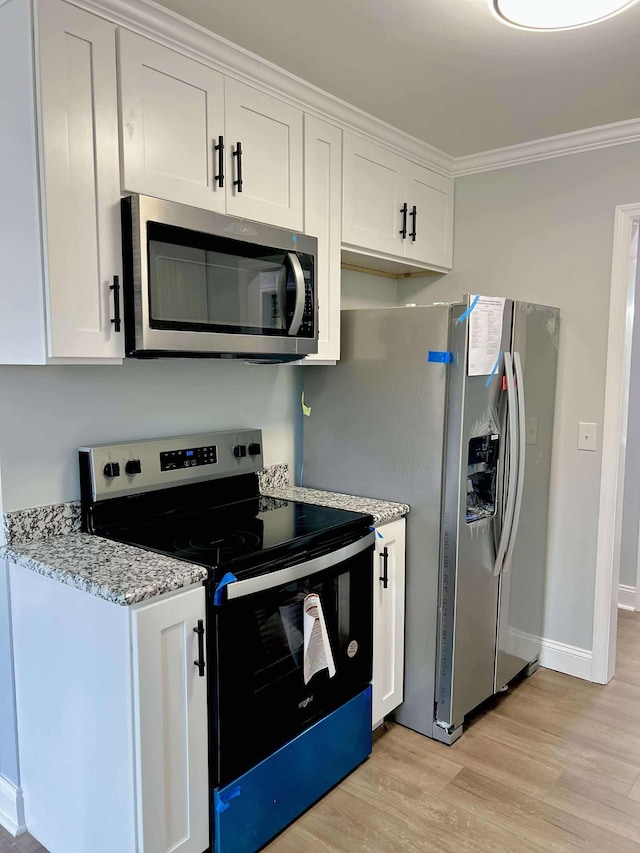 kitchen featuring light stone counters, stainless steel appliances, white cabinets, light wood-type flooring, and crown molding