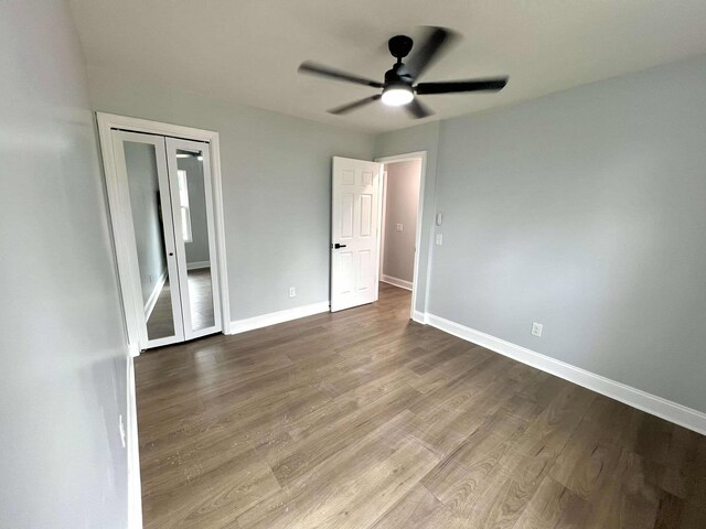 unfurnished bedroom featuring a closet, wood finished floors, a ceiling fan, and baseboards