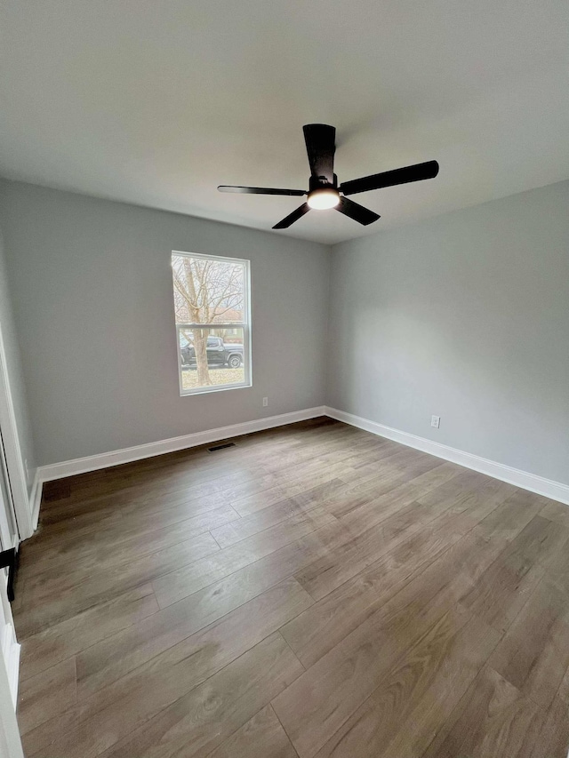 empty room featuring baseboards, visible vents, ceiling fan, and wood finished floors