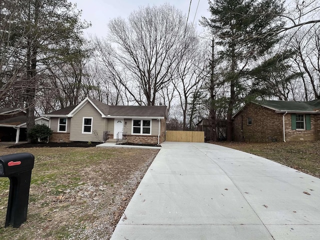 ranch-style house with driveway, fence, and brick siding