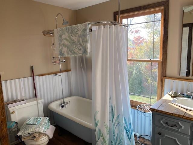 full bath with curtained shower, a soaking tub, plenty of natural light, and vanity