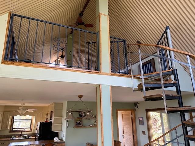 stairs featuring a high ceiling, a ceiling fan, and wallpapered walls