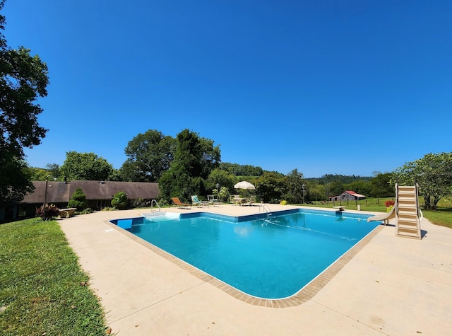 view of pool with a fenced in pool, a yard, a patio, fence, and a water slide