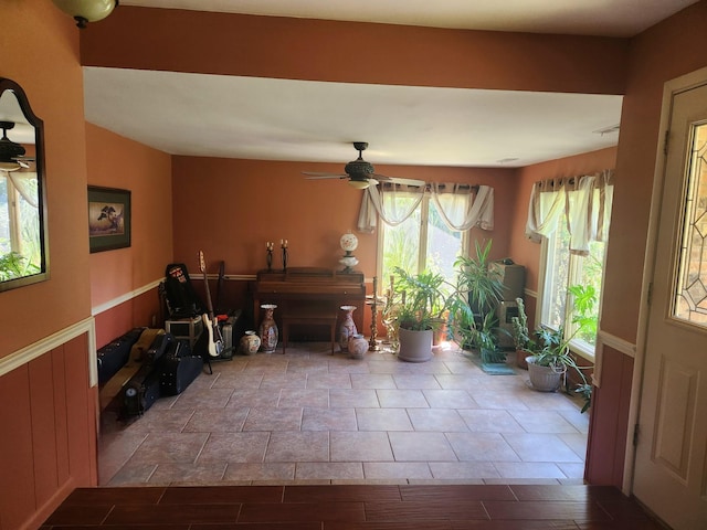 interior space with a wainscoted wall and ceiling fan