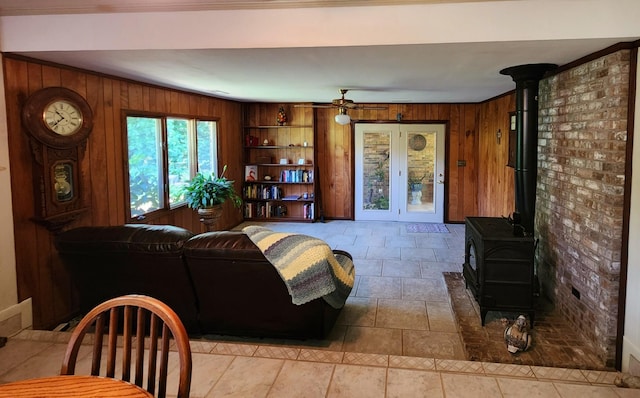 living area featuring wood walls, a wood stove, and a ceiling fan