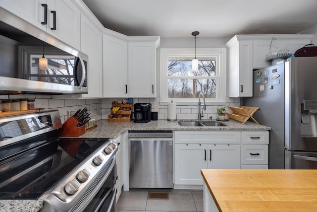 kitchen featuring white cabinets, tasteful backsplash, appliances with stainless steel finishes, and a sink