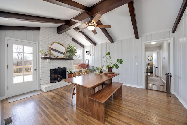 dining space featuring a fireplace, wood finished floors, visible vents, and a wealth of natural light