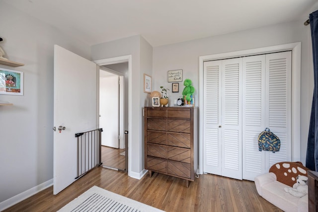 bedroom featuring wood finished floors, baseboards, and a closet