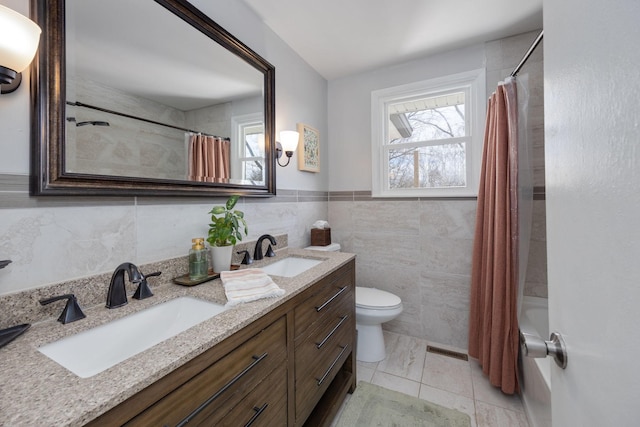 full bath featuring visible vents, toilet, tile walls, and a sink