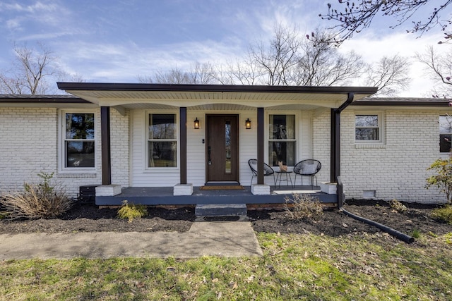 view of front facade with crawl space, covered porch, and brick siding