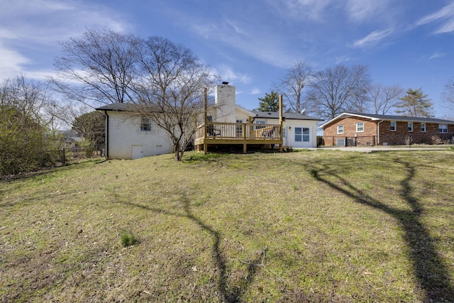 back of property featuring a deck, fence, a yard, brick siding, and a chimney