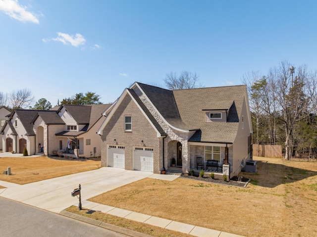 french country style house featuring a porch, concrete driveway, an attached garage, central AC, and a front lawn