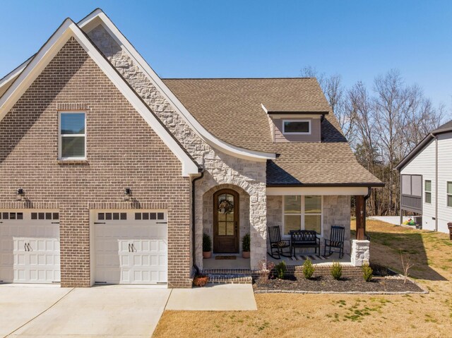 8858 Silver Maple Dr, Ooltewah, TN 37363 - view of front facade featuring driveway, stone siding, roof with shingles, covered porch, and brick siding
