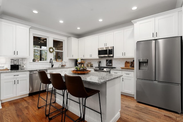 8858 Silver Maple Dr, Ooltewah, TN 37363 - kitchen featuring stainless steel appliances, white cabinets, a sink, and a kitchen bar