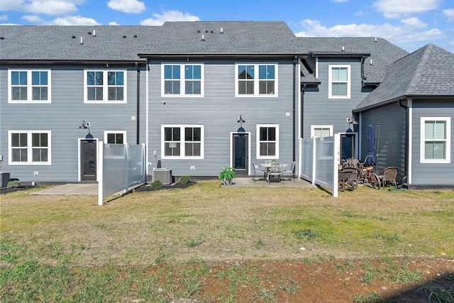 rear view of property with a shingled roof, a lawn, a patio area, and cooling unit