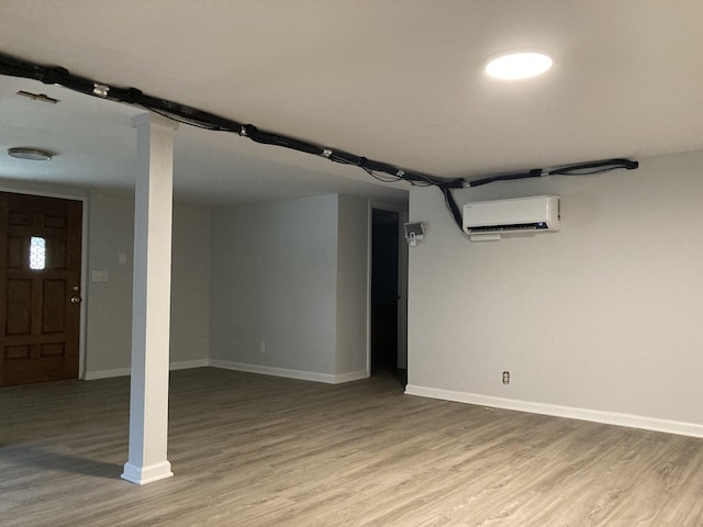 finished below grade area featuring baseboards, wood finished floors, and a wall mounted AC