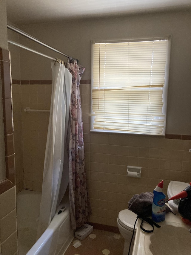 bathroom with toilet, wainscoting, shower / bath combo, and tile walls