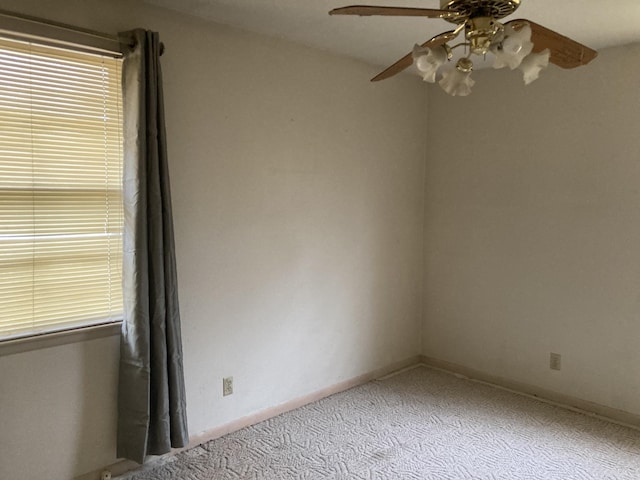 carpeted spare room with a ceiling fan and baseboards