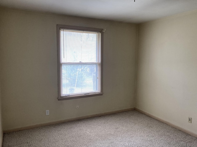 empty room featuring light carpet and baseboards