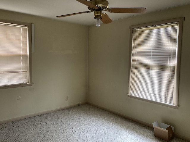 carpeted empty room featuring a ceiling fan, plenty of natural light, and baseboards