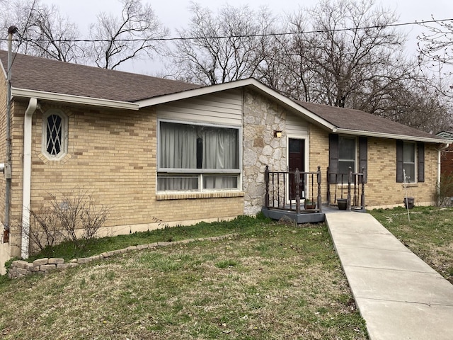 view of front of house with roof with shingles, brick siding, and a front lawn