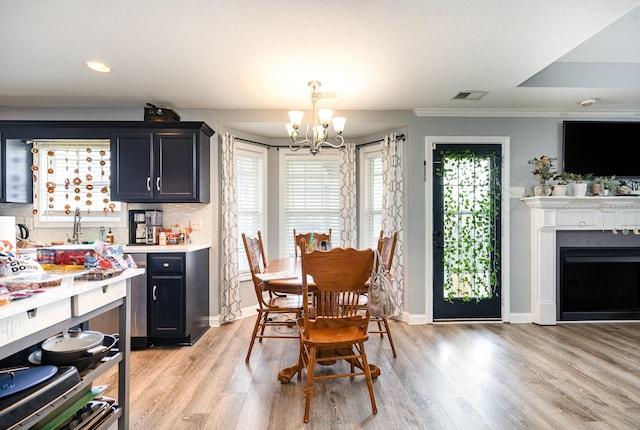 dining area featuring a chandelier, light wood finished floors, visible vents, and baseboards