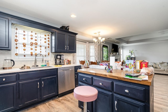 kitchen with light wood finished floors, dishwasher, backsplash, open floor plan, and a sink