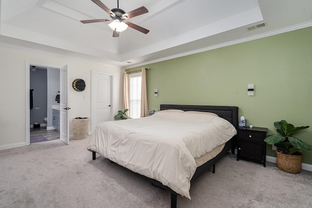 bedroom with light colored carpet, a tray ceiling, visible vents, and crown molding