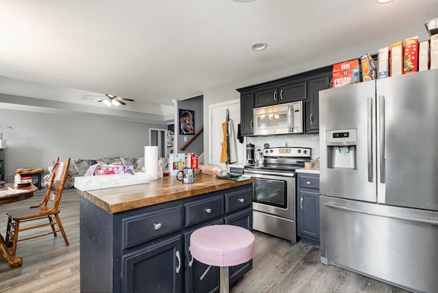 kitchen featuring light wood-style flooring, wood counters, appliances with stainless steel finishes, and open floor plan