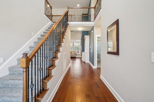 interior space featuring a high ceiling, stairway, baseboards, and wood finished floors