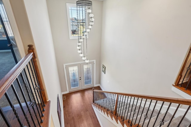 interior space with an upstairs landing, french doors, baseboards, and wood finished floors