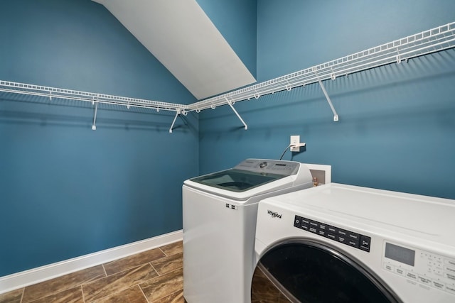 washroom with laundry area, wood finish floors, washer and clothes dryer, and baseboards