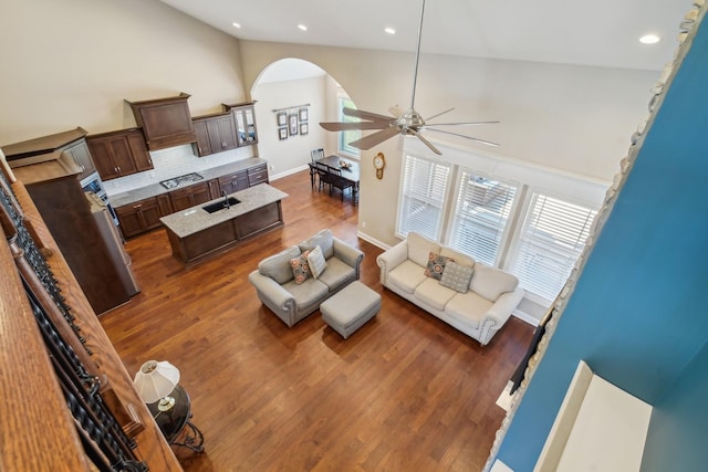 living area featuring arched walkways, dark wood finished floors, recessed lighting, ceiling fan, and high vaulted ceiling